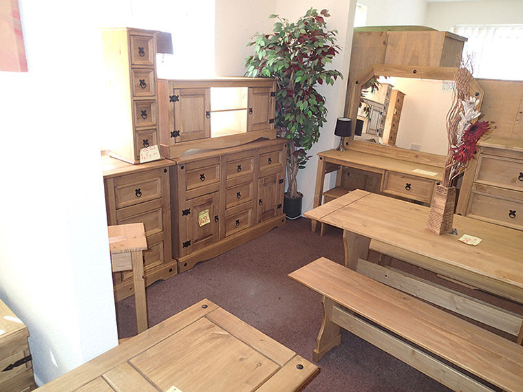 Wooden furniture on display including a desk, draws, and mirror.